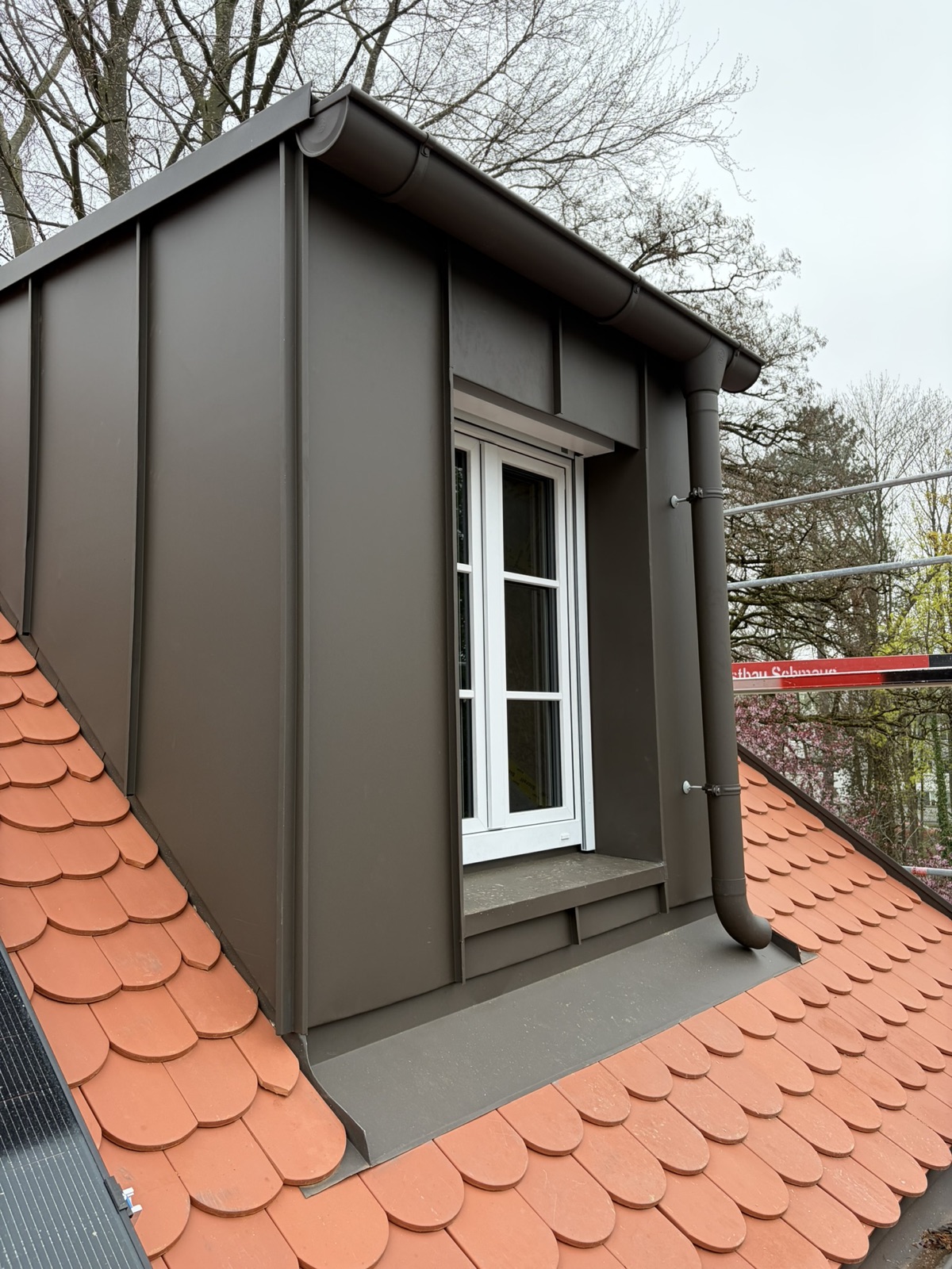 Die neue Gaube mit hinterlüfteter Stehfalz-Fassade in Prefa Braun P10, die Rollladenkästen liegen unsichtbar dahinter.