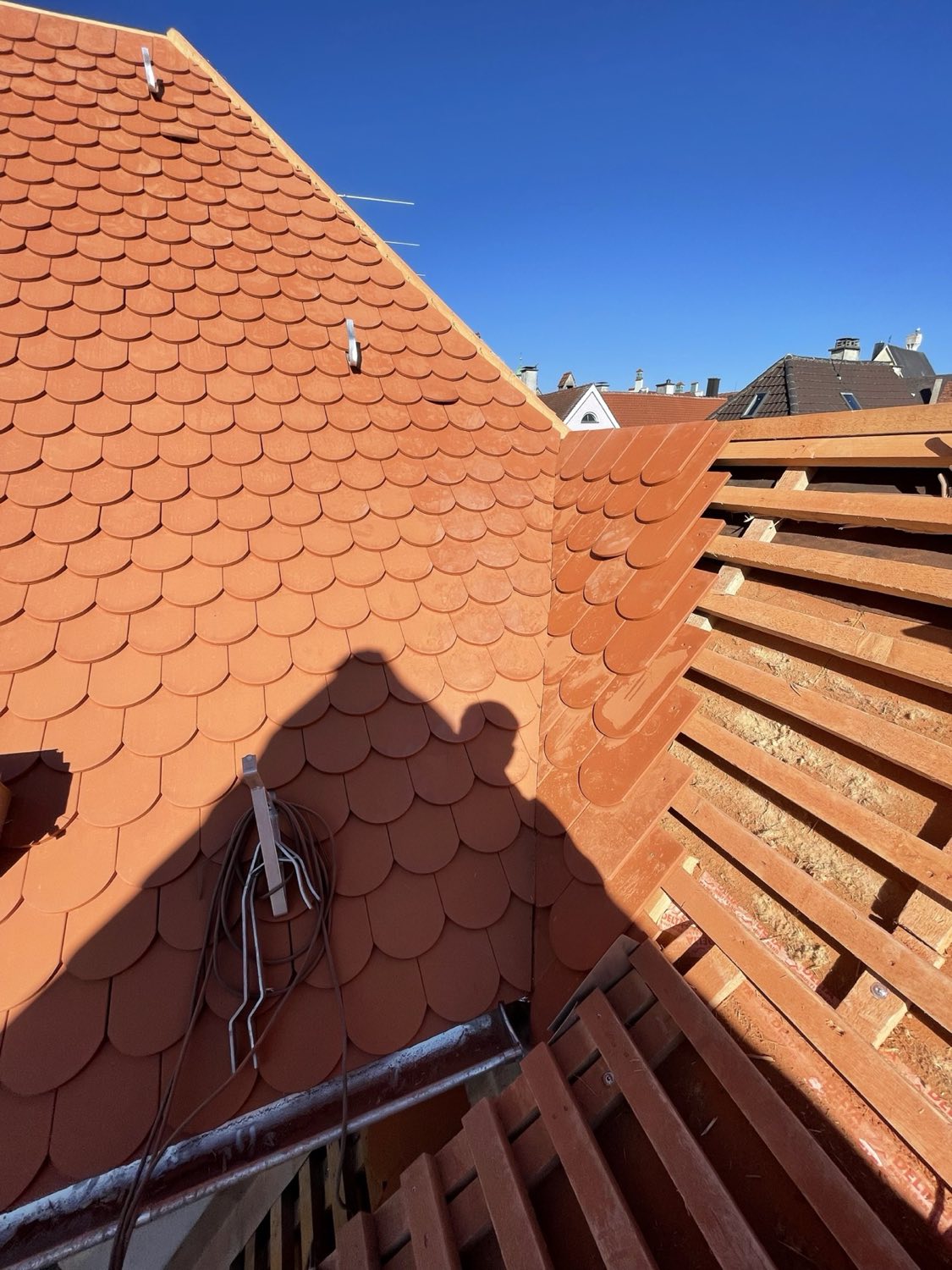 Neuaufbau Schicht für Schicht: frisch eingedeckte Biberschwanzfläche neben der offenen Konterlattung.