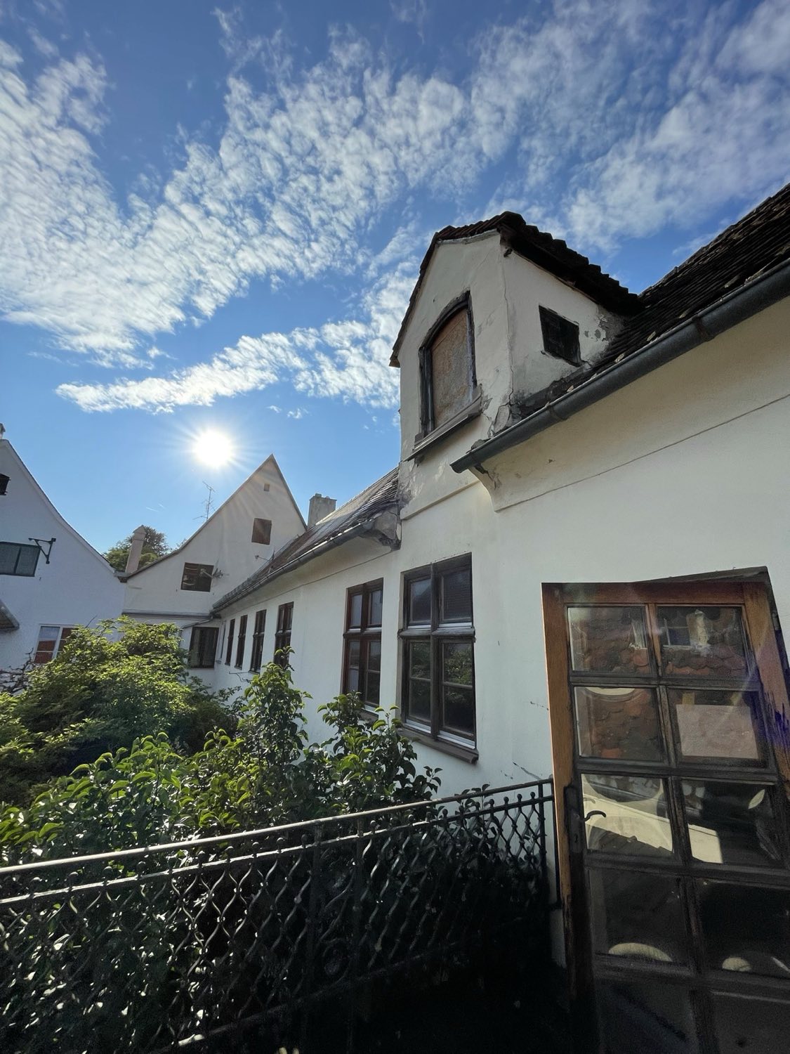 Ausgangslage im Innenhof: verwitterte Substanz und schadhafte Gaube vor der Sanierung.